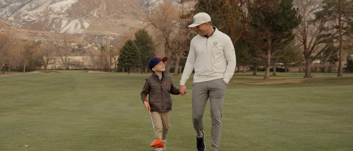 A father and child walking together on a golf course.